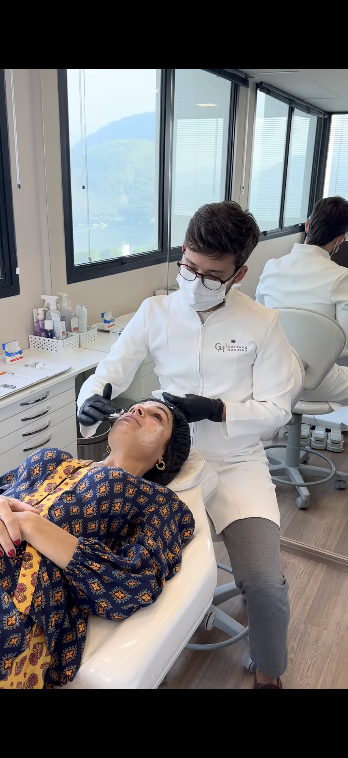 Dr. Gustavo Martins atendendo paciente na Clínica GM, vista da montanha ao fundo
