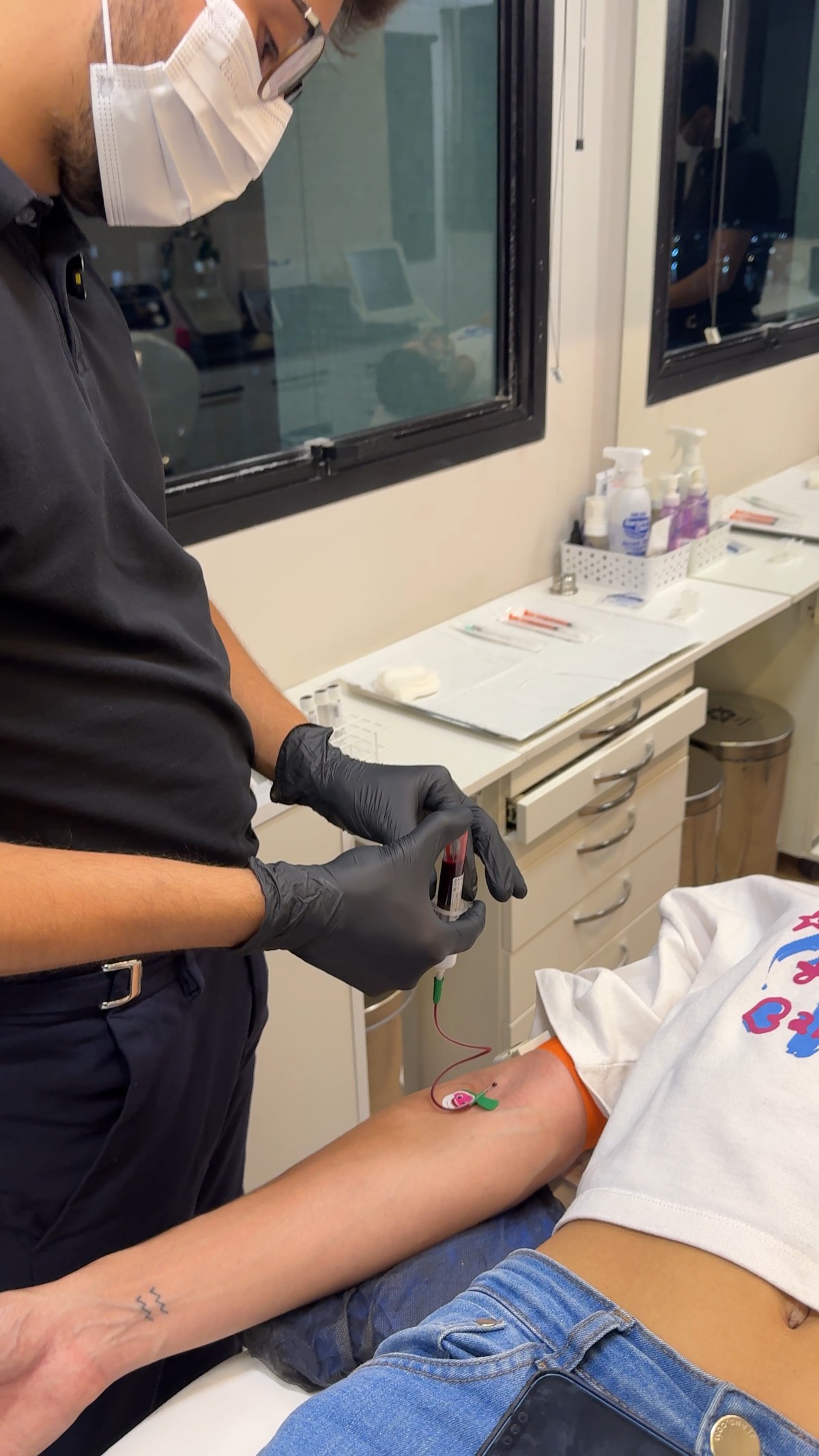 Dr. Gustavo Martins realizando coleta de sangue para protocolo de i-PRF na Clínica Gustavo Martins, Rio de Janeiro. Procedimento com luvas pretas e tubo sem aditivo.